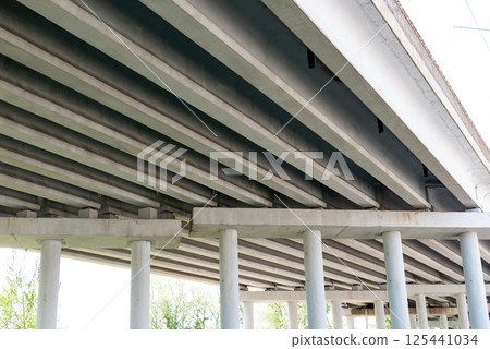 Abstract industrial photo with bottom view of a road bridge with concrete pillars. Abstract industrial photo with bottom view of a road bridge with concrete pillars. 125441034