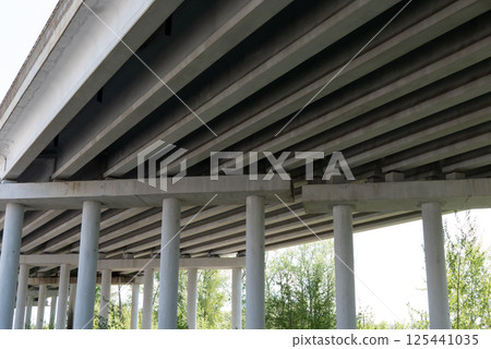 Abstract industrial photo with bottom view of a road bridge with concrete pillars. 125441035