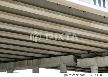 Abstract industrial photo with bottom view of a road bridge with concrete pillars. 125441036