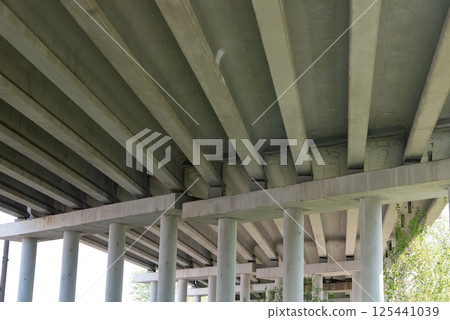 Abstract industrial photo with bottom view of a road bridge with concrete pillars. 125441039