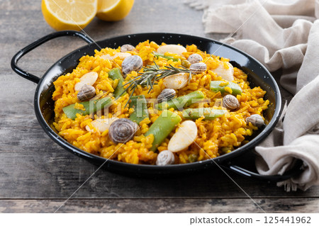 Traditional Valencian paella with rabbit, chicken, garrofon beans, snails, Moroccan green beans and saffron on wooden table Traditional Valencian paella with rabbit, chicken, garrofon beans, snails, Moroccan green beans and saffron on wooden table 125441962
