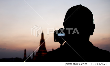 A silhouette of a photographer captures Wat Arun at dusk, emphasizing the passion for travel and photography with a serene twilight backdrop. A silhouette of a photographer captures Wat Arun at dusk, emphasizing the passion for travel and photography with a serene twilight backdrop. 125442672