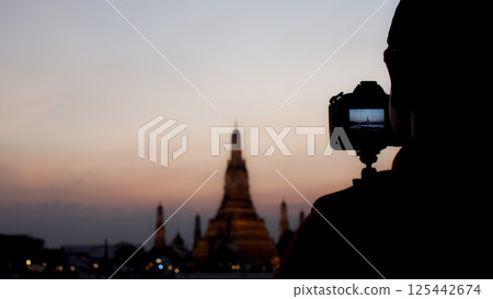 Camera silhouette capturing Wat Arun at sunset, Bangkok, Thailand. Perfect for travel and photography themes. 125442674