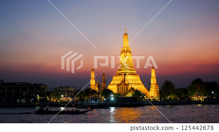 Scenic twilight view of Wat Arun illuminated against a vivid sunset sky, with reflections on the Chao Phraya River. Perfect for travel, culture, and destination themes. 125442678