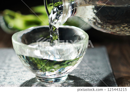 Sake and edamame being poured Sake and edamame being poured 125443215