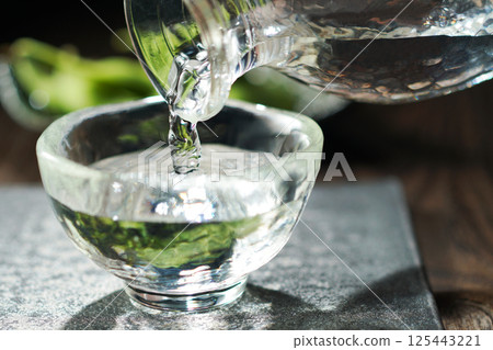 Sake and edamame being poured Sake and edamame being poured 125443221