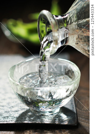 Sake and edamame being poured Sake and edamame being poured 125443334