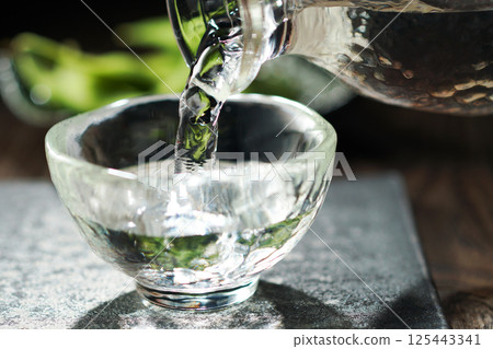 Sake and edamame being poured Sake and edamame being poured 125443341