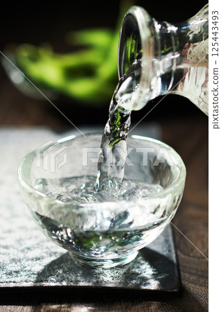 Sake and edamame being poured Sake and edamame being poured 125443493