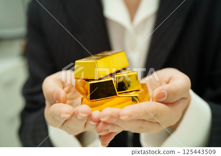 Asian woman holding gold bar in finance business. 125443509