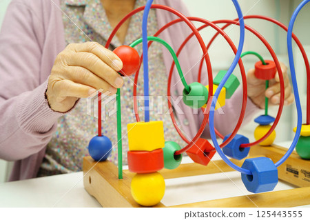 Asian elderly woman playing enhancing skill board game. 125443555
