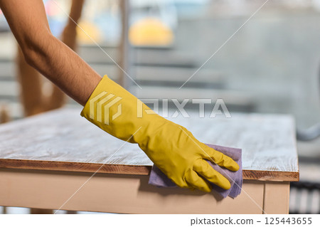 Effectively Cleaning A Table Surface With A Sponge For A Neat And Tidy Appearance 125443655
