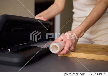 Hands Skillfully Preparing Vacuum Sealing for Food Preservation and Storage Purposes Hands Skillfully Preparing Vacuum Sealing for Food Preservation and Storage Purposes 125443964