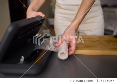 Hands Skillfully Preparing Vacuum Sealing for Food Preservation and Storage Purposes 125443967