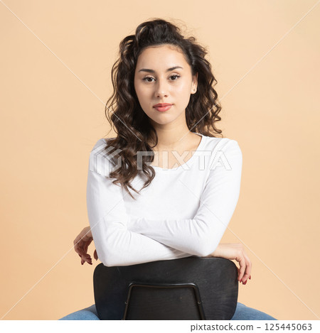 Studio portrait of woman sitting on chair 125445063