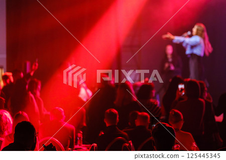 Live concert with crowd experiencing vibrant red lights and entertaining performance Live concert with crowd experiencing vibrant red lights and entertaining performance 125445345
