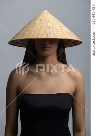 Beautiful woman with Asian cane hat studio portrait 125445489