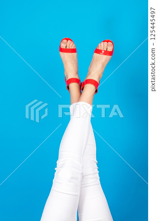 Woman legs with white trousers and red shoes 125445497