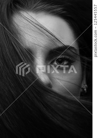 Woman portrait with part face covered with hairs by blowing wind 125445557