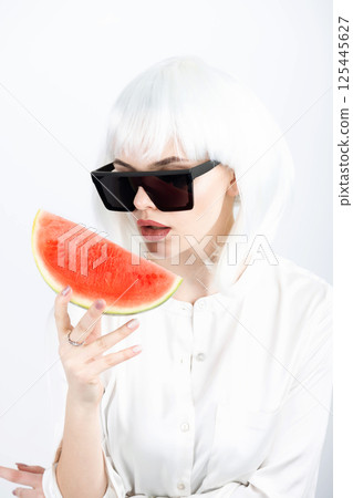 Woman with white wig holding slice of red watermelon 125445627