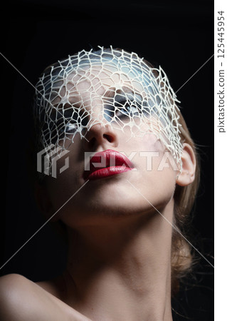 Beautiful woman with fancy make-up and abstract face mask studio portrait Beautiful woman with fancy make-up and abstract face mask studio portrait 125445954