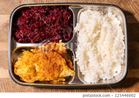 A metal food tray with three compartments: red beets in one, a fried cutlet in another, and white rice in the third. 125446002