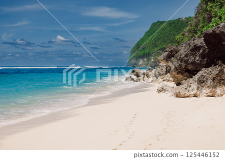 Tropical beach with ocean and cliff rocks. Holidays in luxury paradise island Tropical beach with ocean and cliff rocks. Holidays in luxury paradise island 125446152