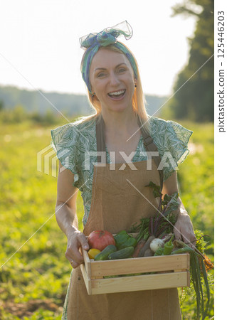 Portrait of beautiful woman picking up vegetables in garden Portrait of beautiful woman picking up vegetables in garden 125446203
