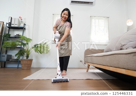 Housekeeping and Family Togetherness. A mother vacuums the floor while enjoying a moment of cleanliness. Housekeeping and Family Togetherness. A mother vacuums the floor while enjoying a moment of cleanliness. 125446331