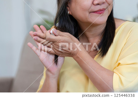 Nourishing Hair and Beauty. A woman applying hair serum for healthy locks. 125446338