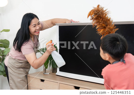 Family Cleaning and Fun. A woman and child cleaning together with a spray bottle and feather duster. Family Cleaning and Fun. A woman and child cleaning together with a spray bottle and feather duster. 125446351
