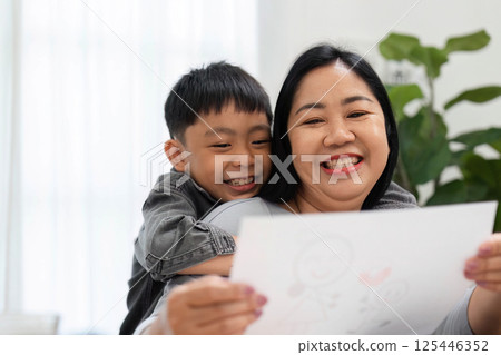 Creative Moments and Family Love. A mother and her son share a loving embrace while admiring his artwork. 125446352