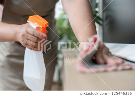 Cleaning and Home Care. A person using a spray bottle to clean a surface. Cleaning and Home Care. A person using a spray bottle to clean a surface. 125446356