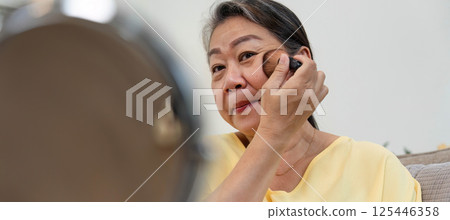 Beauty and Age Diversity. A senior woman applying foundation while enjoying her beauty routine. Beauty and Age Diversity. A senior woman applying foundation while enjoying her beauty routine. 125446358