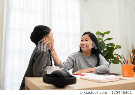 Encouragement and Connection. A mother shares a warm moment with her son, fostering a supportive atmosphere during study time. 125446361