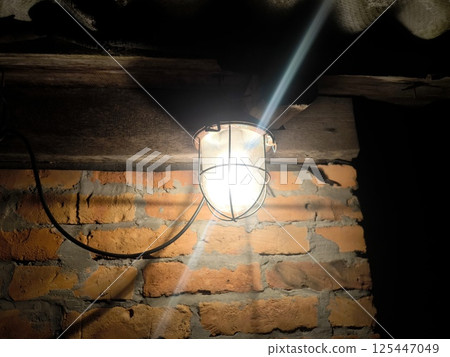 old fashioned hanging street lamp outdoors. An old-fashioned hanging street lamp on the background of a red brick wall. Night. An old street lamp in the village 125447049