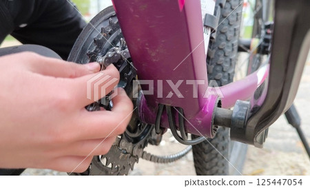 Bicycle breakdown. A boy repairs a bicycle chain outdoors. Work by hand. using a bicycle chain. 125447054