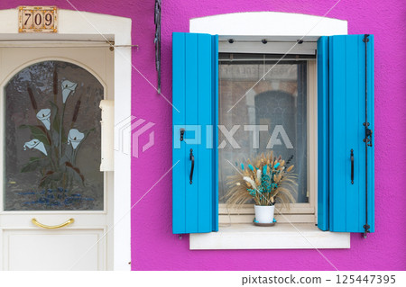 Magenta facade with blue shutters in Burano Magenta facade with blue shutters in Burano 125447395