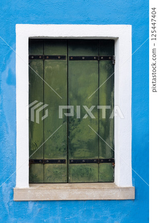 Old green shutter on blue wall in Burano Old green shutter on blue wall in Burano 125447404