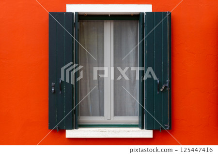 Green shutters on vivid red wall 125447416