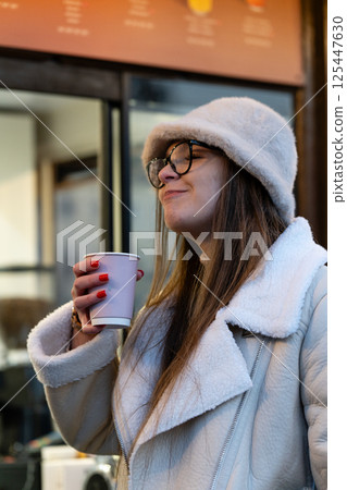 Enjoying a cozy moment sipping warm beverage outside a city cafe on a chilly afternoon, captured in soft light that enhances the scene's warmth and comfort Enjoying a cozy moment sipping warm beverage outside a city cafe on a chilly afternoon, captured in soft light that enhances the scene's warmth and comfort 125447630