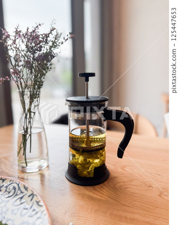 A glass teapot with herbal infusion on a cafe table. Calmness, wellness and slow living through everyday rituals 125447653
