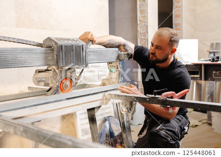 Construction worker cutting tile with tile saw during renovation works 125448061