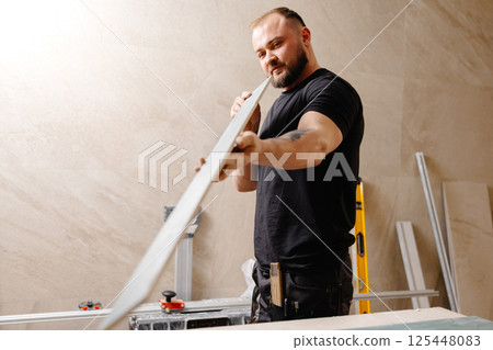 Construction worker checking large ceramic tile during renovation works 125448083