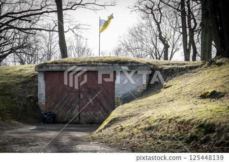 Flag of Ukraine Above a Rustic Garage with Red Wooden Doors 125448139