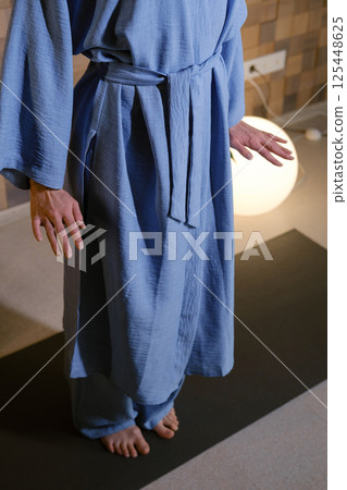 Girl in blue kimano practicing kundalini or qigong yoga in fitness gym . Spiritual energy, life force located at the base of the spine Girl in blue kimano practicing kundalini or qigong yoga in fitness gym . Spiritual energy, life force located at the base of the spine 125448625