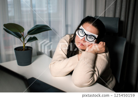 Tired business woman with painted eyes on adhesive notes having fatigue and headache during work in office. Female feeling stressed and exhausted from overworking Tired business woman with painted eyes on adhesive notes having fatigue and headache during work in office. Female feeling stressed and exhausted from overworking 125450159