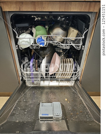 Open dishwasher containing dirty dishes waiting to be washed Open dishwasher containing dirty dishes waiting to be washed 125451151