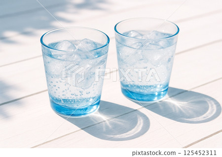 白色木桌上的藍色玻璃杯中閃閃發光的水 白色木桌上的藍色玻璃杯中閃閃發光的水 125452311