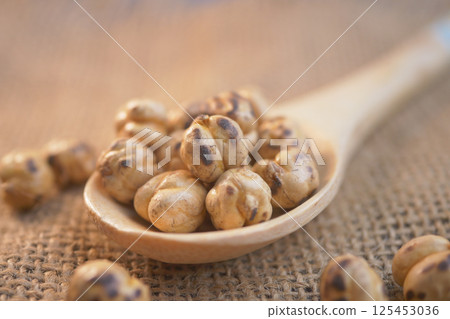 Roasted chickpeas on a wooden spoon against a burlap background 125453036